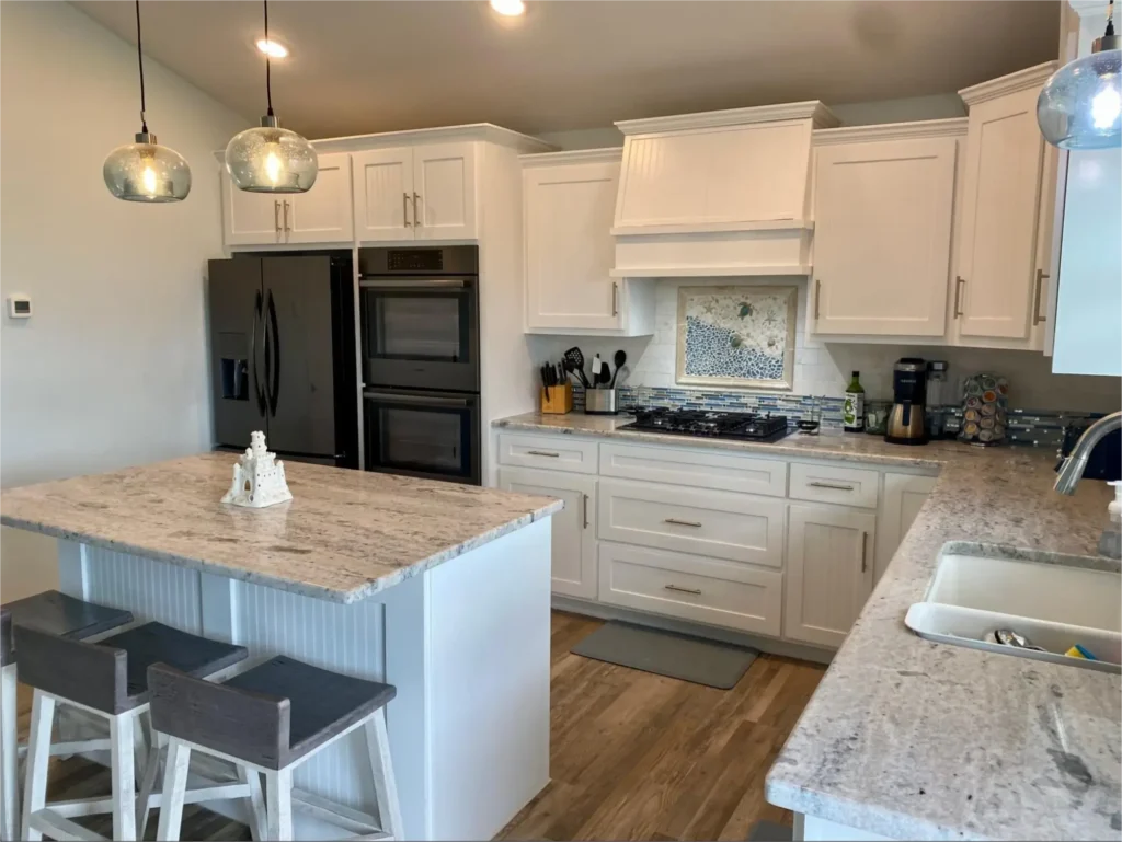 White kitchen with island and lighting.