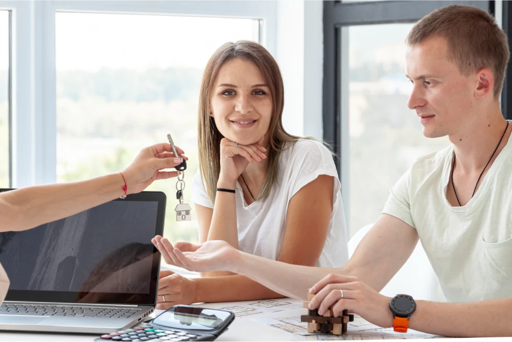 A couple receiving house keys from a real estate agent, symbolizing a successful home purchase.