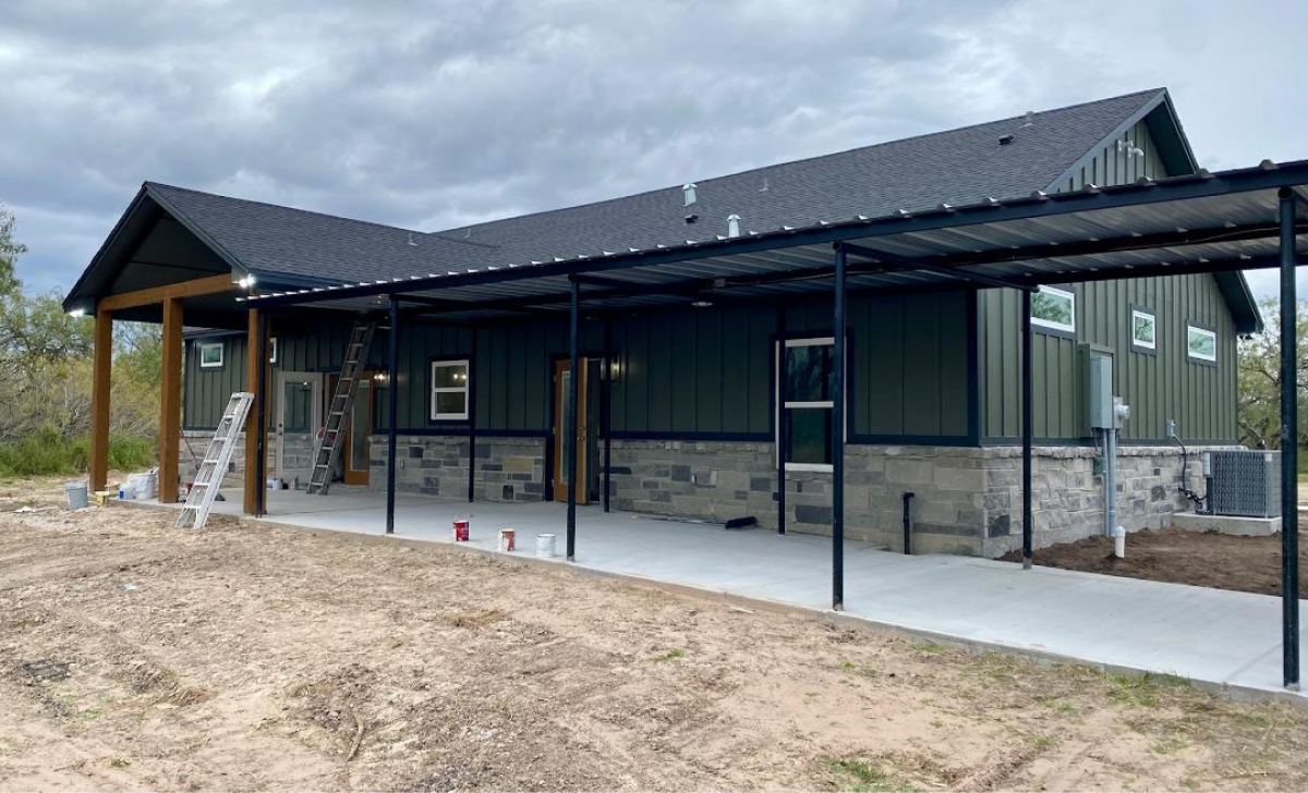 Green house with stone siding and patio.