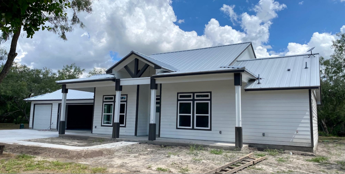 White farmhouse with black accents and porch.